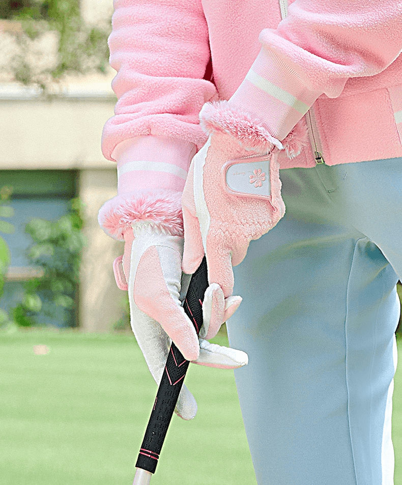 Woman wearing stylish pink anti-slip warm gloves, holding a golf club outdoors.